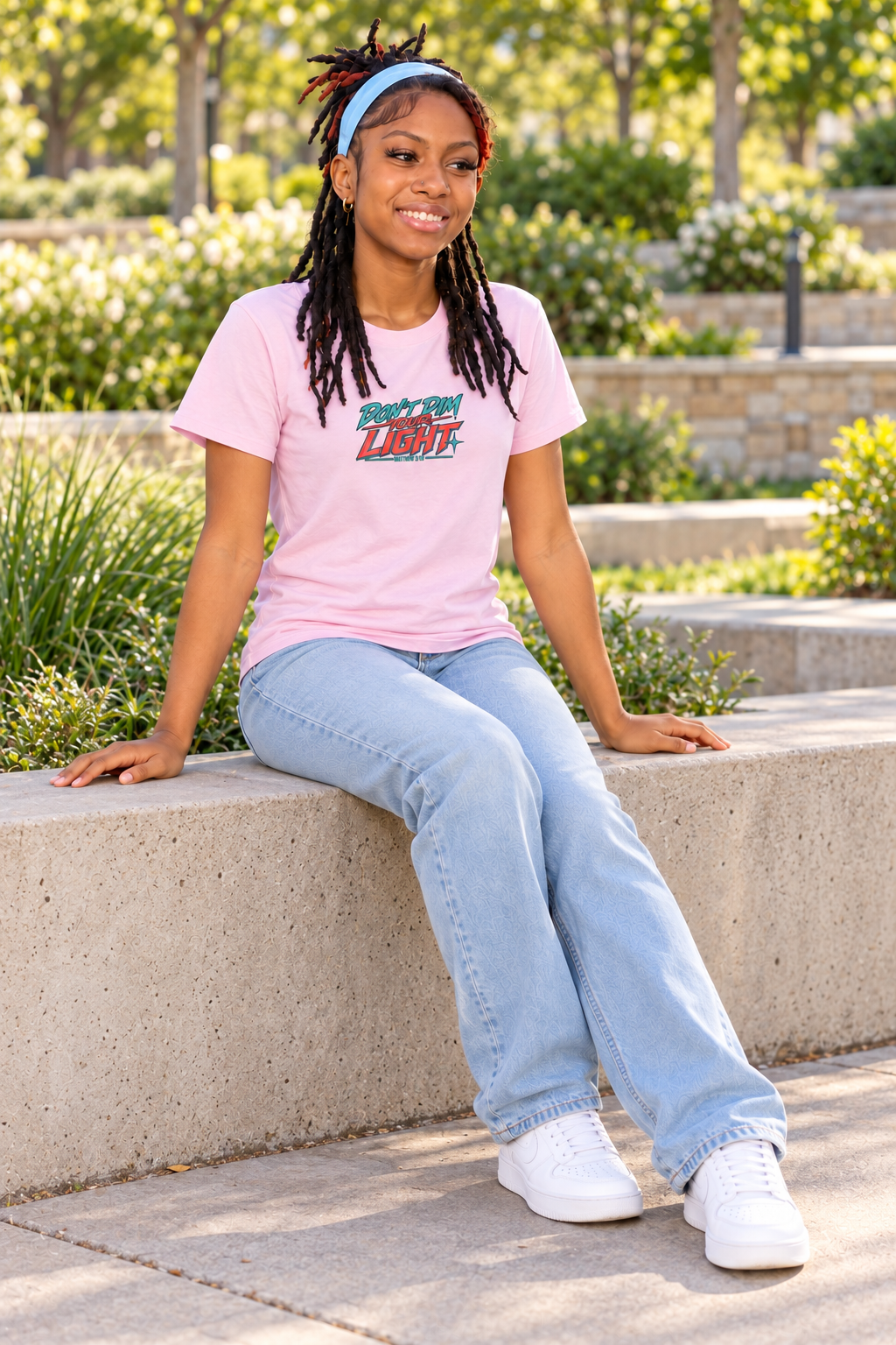 Child seated in a pink Don’t Dim Your Light 7Fold tee